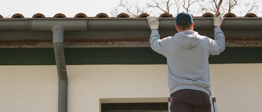 Handwerker montiert eine neue Dachrinne an einem Wohnhaus
