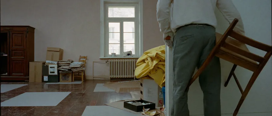 Helfer trägt einen alten Stuhl aus einer vollgestellten Wohnung